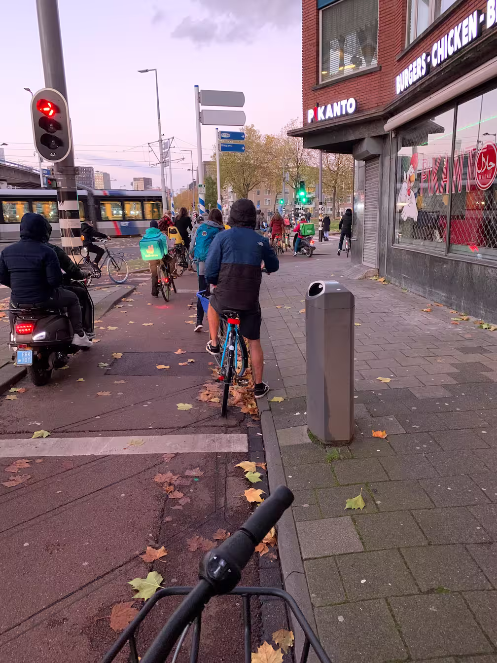 Deliveroo en Uber Eats fietsers op het fietspad met een tram bij Maashaven